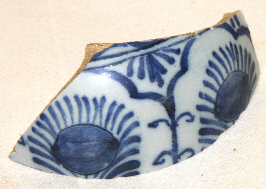 1 skulderskår fra kraftig rundbuget krukke af blådekoreret fajance med stiliseret blomstermotiv i arkadeindraming.