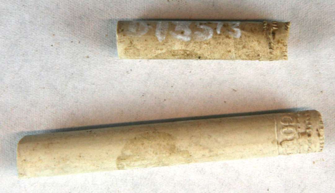 2 fragmentstumper af kridtpibestilke med svagt indpressede bælter i tandsnitmønster og tillig forsynet med indskriftbånd i ophøjet relief: IN GOUDA. Mål: 3 og 5,2 cm.