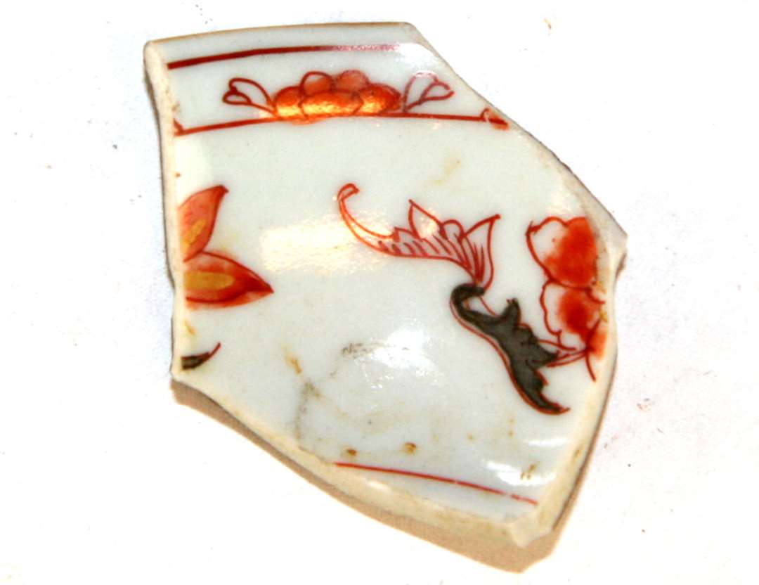 Rand/sideskår fra kop af kinesisk porcellæn med brun glasur på ydersiden og dekoration med blomstermotiver i rødbrunt med guld samt gråt på indersiden.