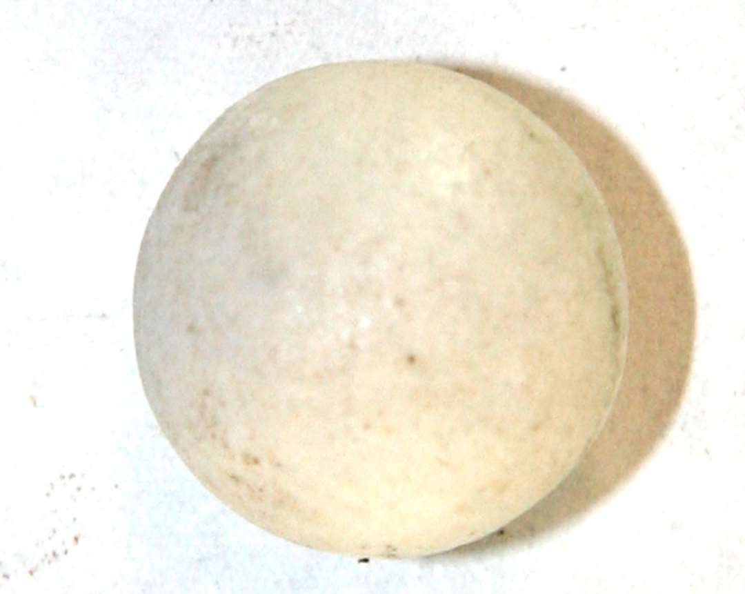 1 marmorkugle af lidt uregelmæssig form af hvidgråt marmor med svage spor af en ca. 1 mm. bred påmalet gråblå omkringløbende midterstribe. Diameter: 1,6 - 1,7 cm.