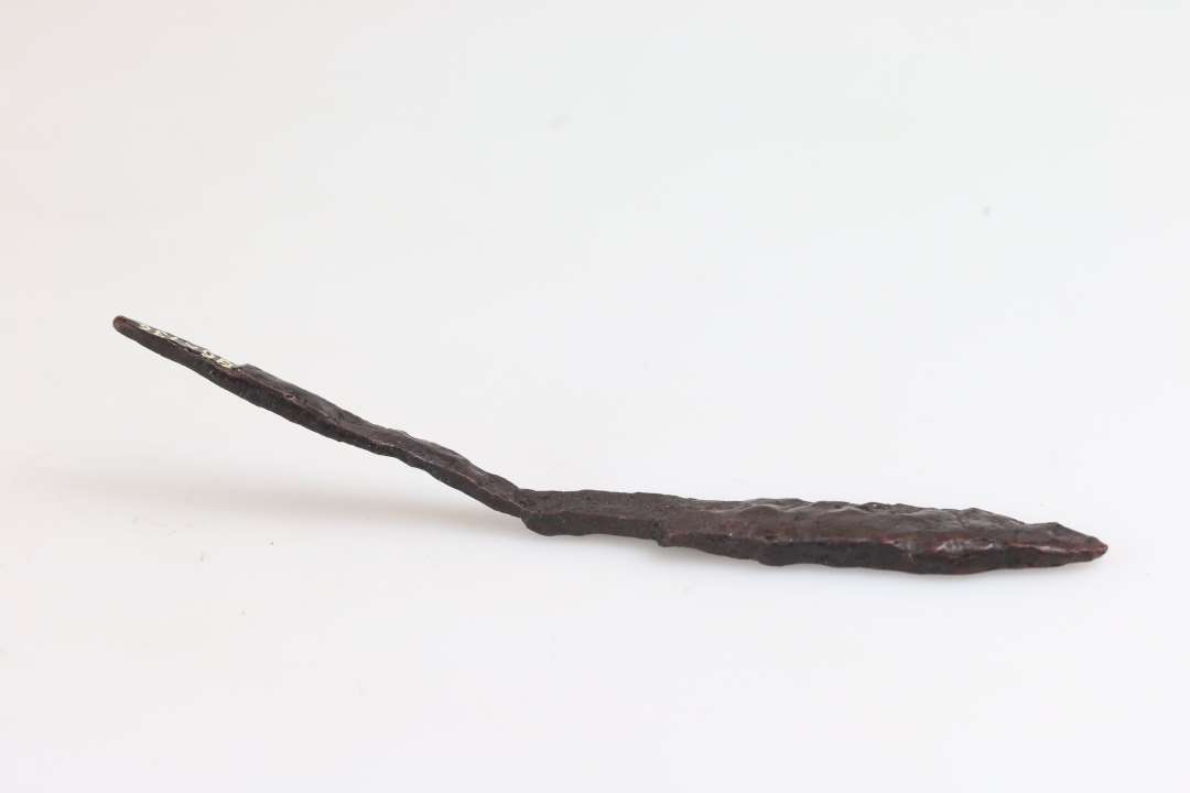 1 jernkniv med bøjet grebtunge og smalt blad. Længde 12,5 cm, blad bredde 1,2 cm, blad tykkelse 0,4 cm.