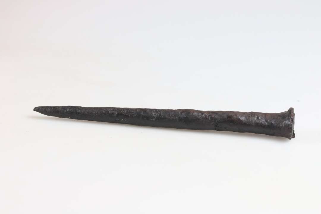 Dorn af jern, længde 16,5 cm, med fladt udhamret hoved, tilspidset i enden ende.