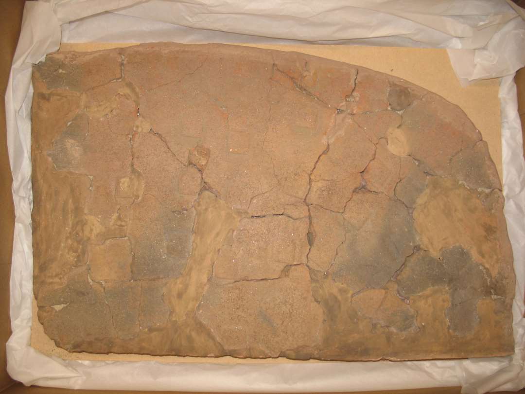 Fragmenter fra lerbelægning på ildsted. En 1/4-del af ildstedet samlet. Mål: 58x36 cm. Overfladen ornamenteret med indpressede kvadrater.