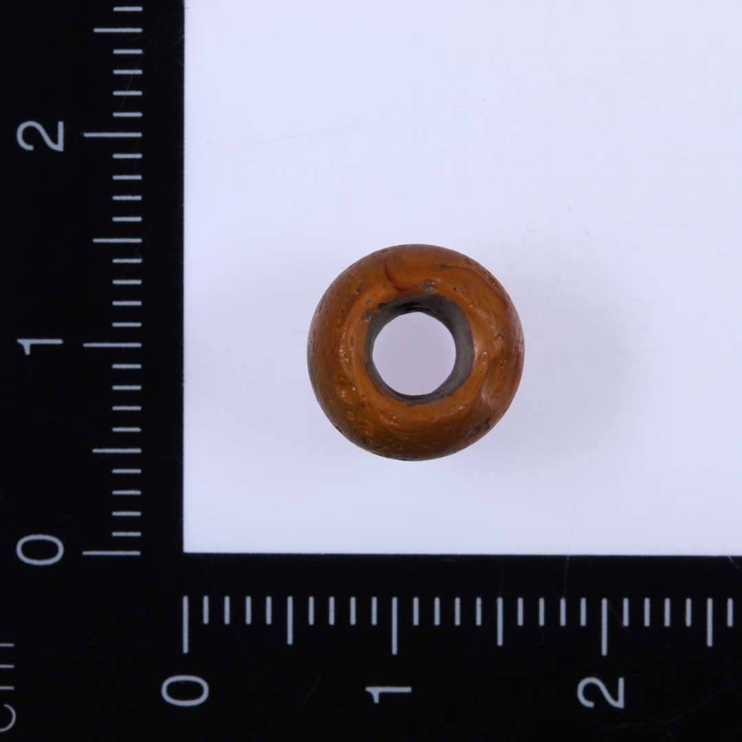 Rødgul perle, diameter 1,0 cm, længde 0,6 cm med gennemboring.