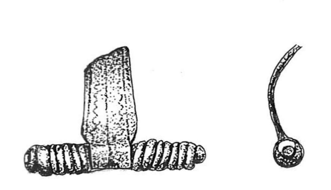 Fragment af bronzefibel. Længde: 3 cm. Optaget i præp. sammen med en ubestemmelig klump jern.