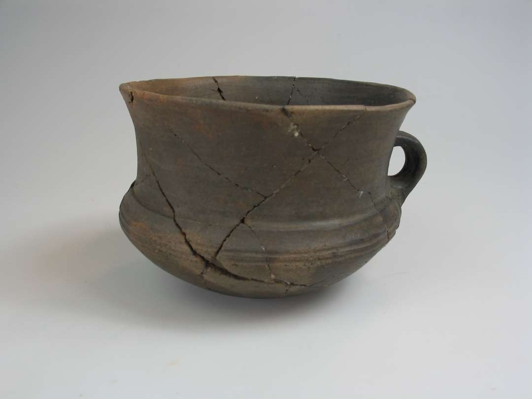 Vaseformet lerkar med hank. Glittet/ornamenteret yderside og inderside. Højde: 11 cm., mudingsdiameter: 14,5 cm.