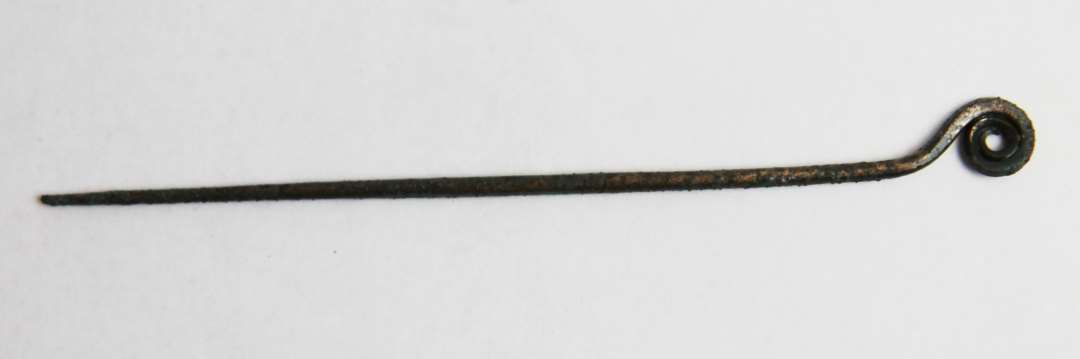 Bøjlenål af bronze med oprullet hovede. Længde 13,7 cm. 