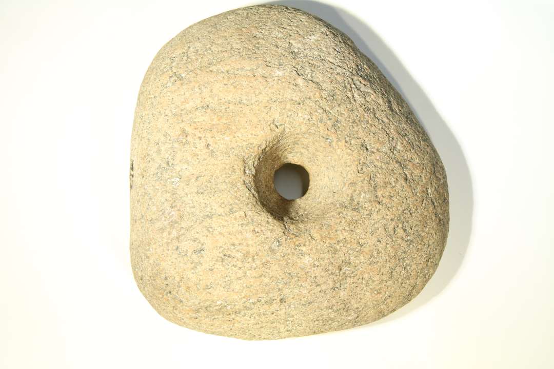 Granitsten med hul. stenen er uregelmæssig i formen, ca. 19cm i dm,- 6cm tyk, hullet er konisk fra begge sider, yderst 5cm, inderst 2cm. 