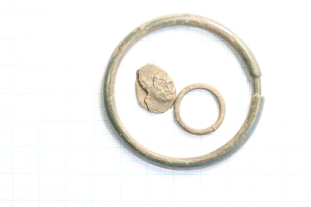 Tre genstande af bronze. To ringe, 1 stk.: diameter: 1,8 cm. 1 stk. diameter: 6 cm. Samt et mindre fragment, måske med rest af nitte. funktion?