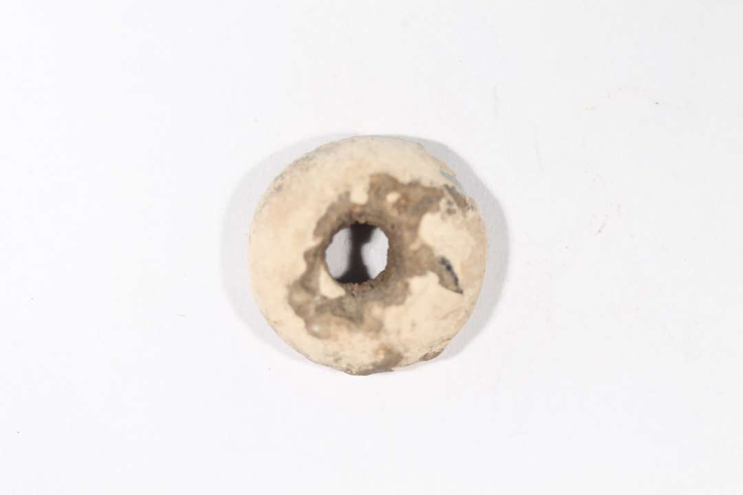 Tenvægt. Cirkulær, med flad underside og hvælvet overside. Diameter: 2,2 cm.
