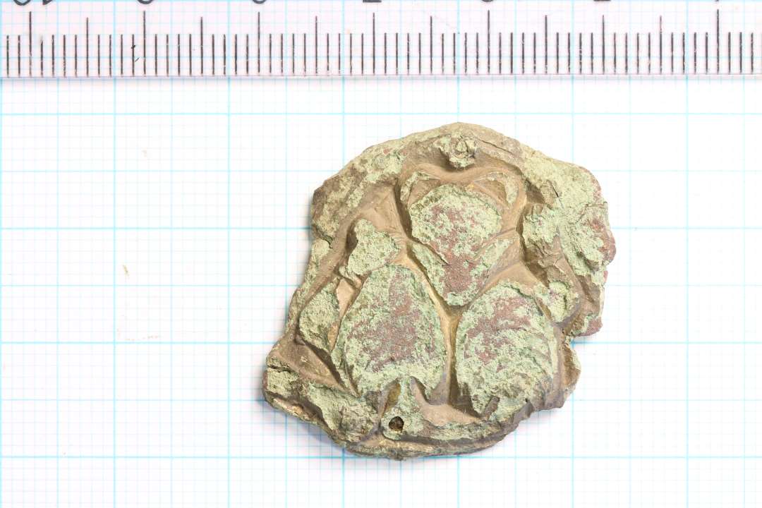 Fragment af forgyldt fibel eller lignende, vikingetid? Plastisk dekoration hvori indgår gribedyr. Rester af forgyldning. Største mål: 3,7x2,5 cm.