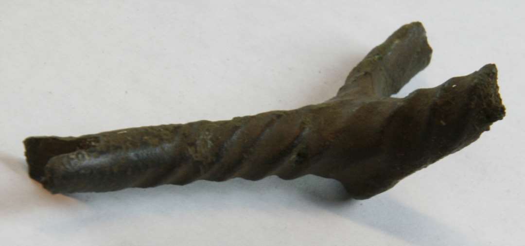 Fragment af hjulspore af kobberlegering. Størstedelen af grenene er knækket af, samt det yderste af sporen. Ornamenteret med snoninger på gren og hals. Fragmentets længde: 6,5 cm. 1300-1400-tallet.