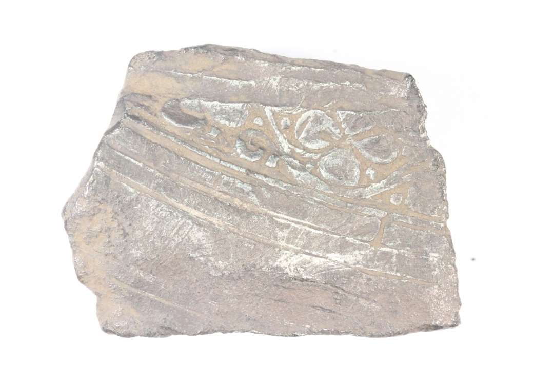 Del af romersk sølvkar med standring. Indersiden med firkløver og rankeslyngsdekoration. Standringens oprindelige diameter: ca 10 cm., stykkets mål: 4,2x3,2 cm.