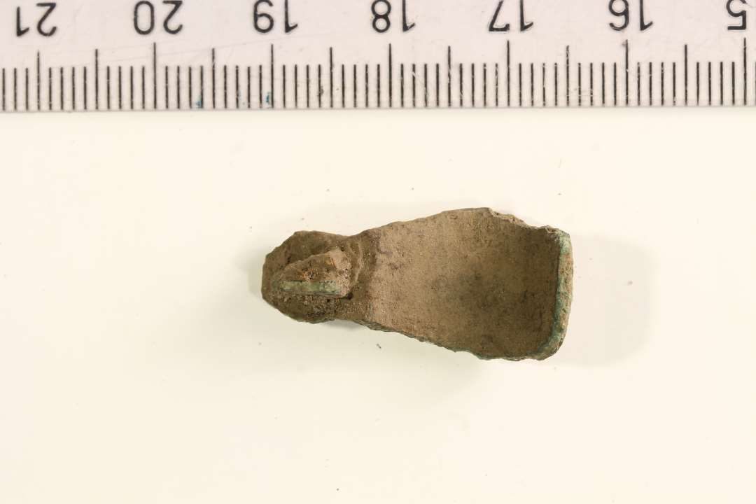 Fragment af kort ligearmet fibel. Dekoration med tværrifling. Længde: 2,5 cm.
