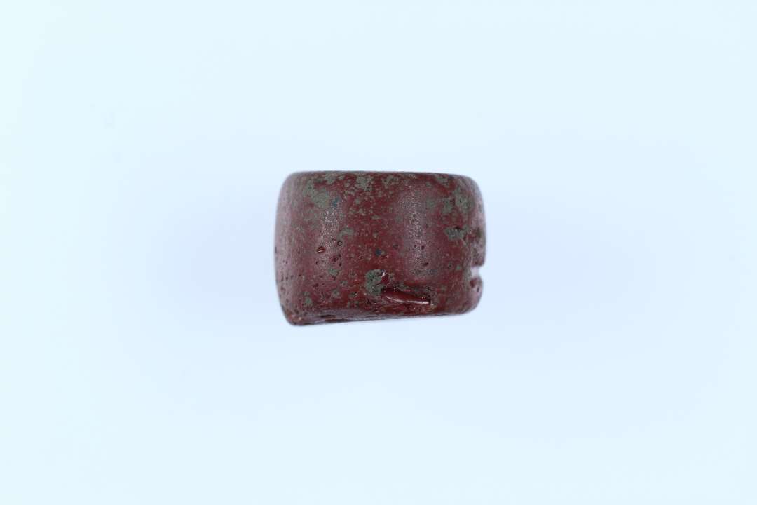 Perle, Tøndeformet, af rødbrunt glas. Diameter: 1 cm.
