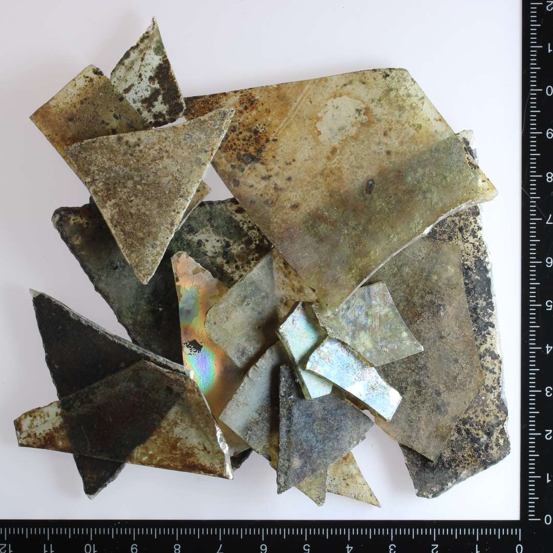 Både tyndt og tyk vinduesglas, flere stykker med krøselbid og trekantet eller rhombisk form. Et af stykkerne er blåt glas