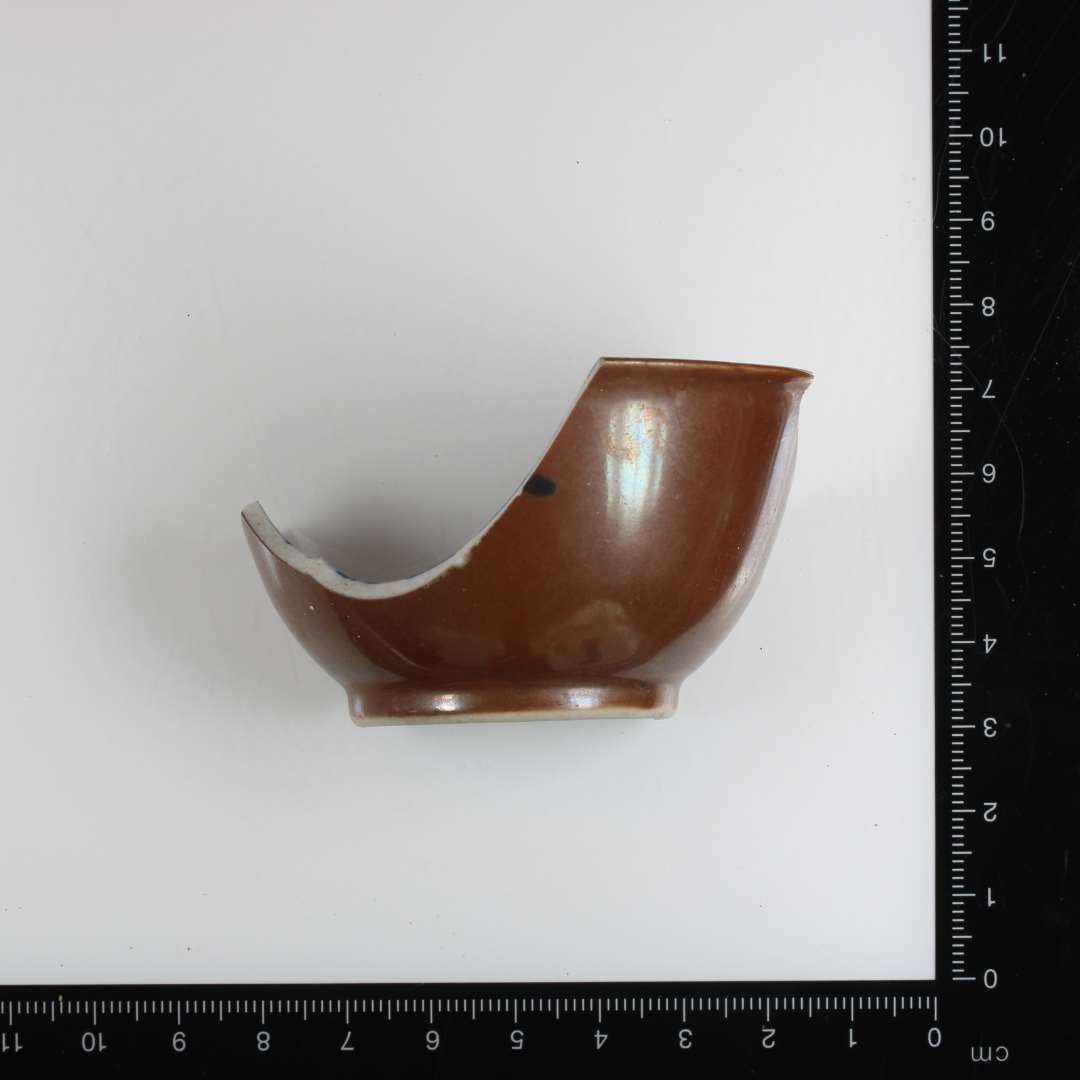Stort skår af lille porcelænskop h. 42 mm, ø ca. 70 mm. Udvendig brun glasur, indvendig klar hvid med blå, malet dekoration. Import fra Kina.
